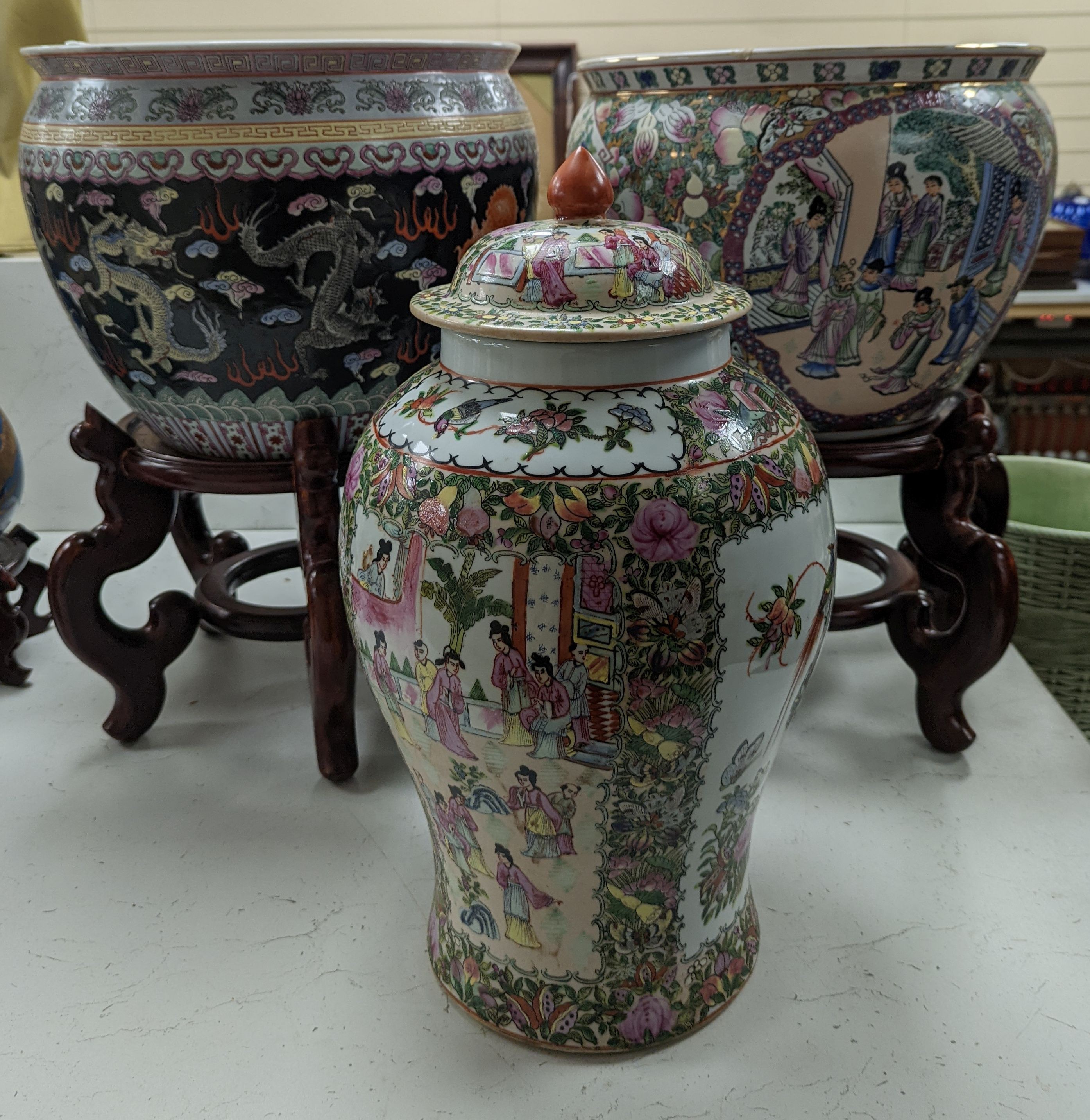 A pair of Chinese fish bowls on hardwood stands and a similar jar and cover, Fish bowls and stands 54 cms high.